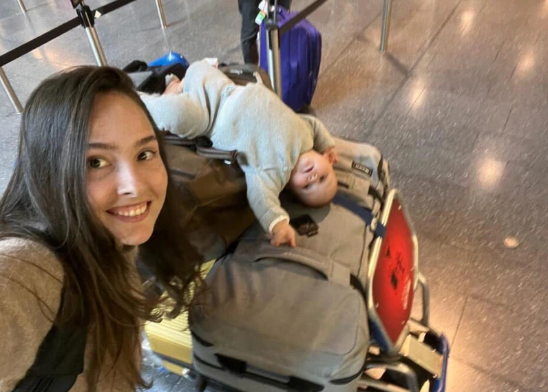 A Konpo team member's airport selfie, with a baby asleep on the luggage trolley