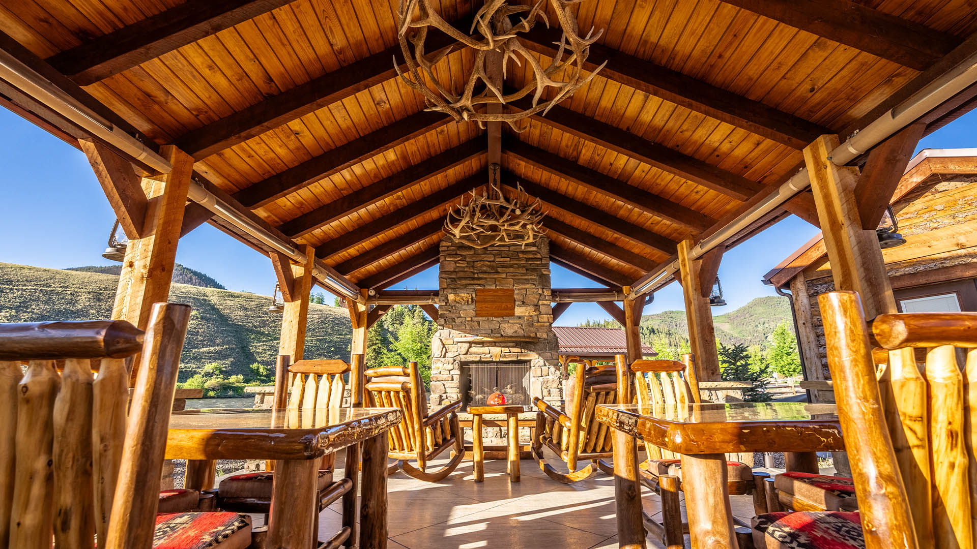 Outdoor pavilion with antler chandelier and stone fireplace