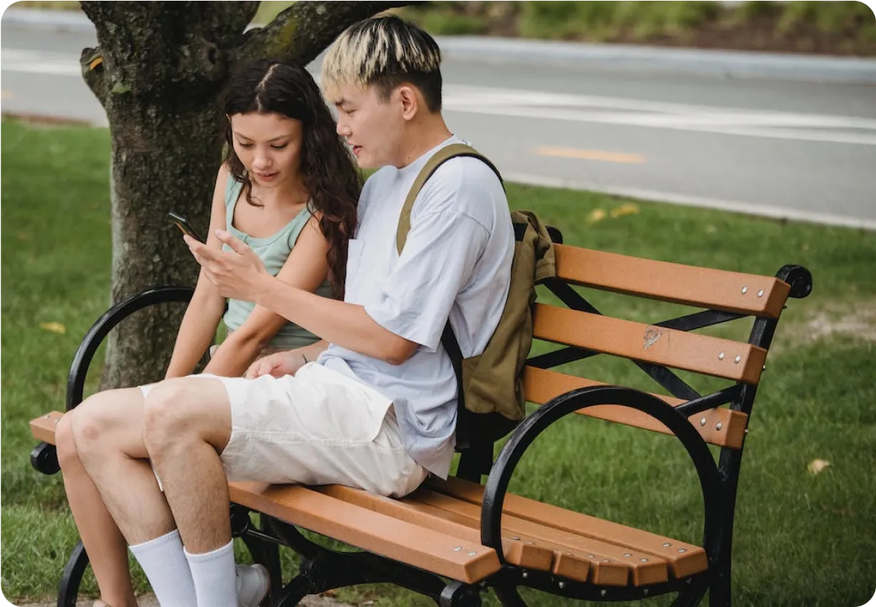 Two young adults sitting on a park bench. 