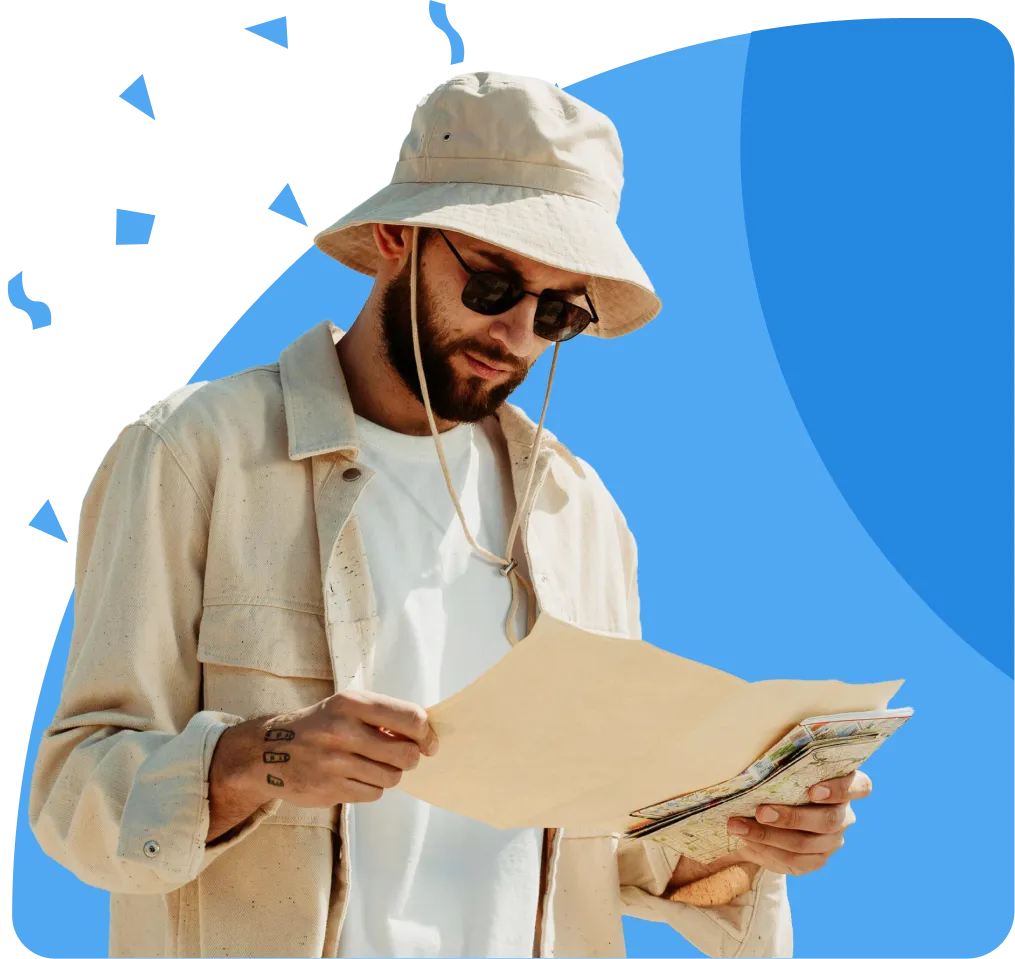 Man with beard, beige jacket, bucket hat, sunglasses, holding map. Tattoo on forearm, blue background with triangles.