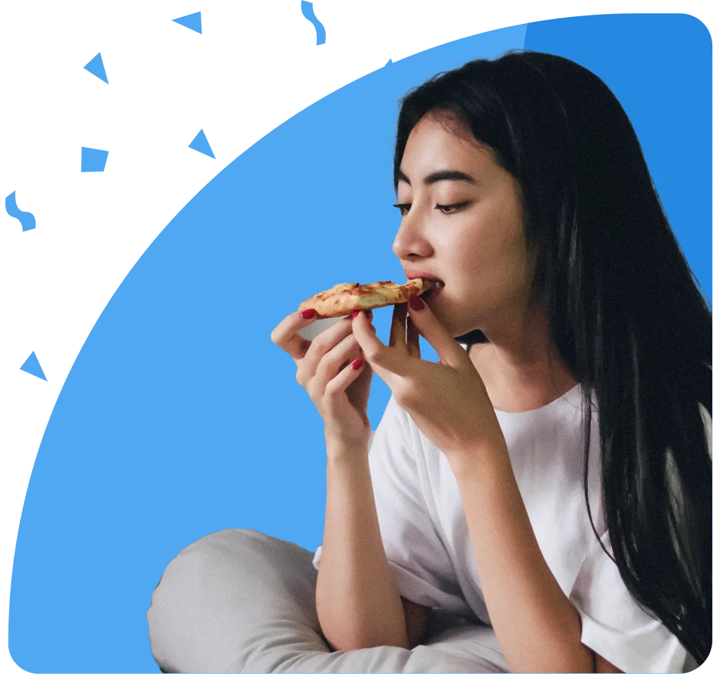 Woman in a white t-shirt eating pizza, red nails stand out against pale skin, vibrant light-blue background
