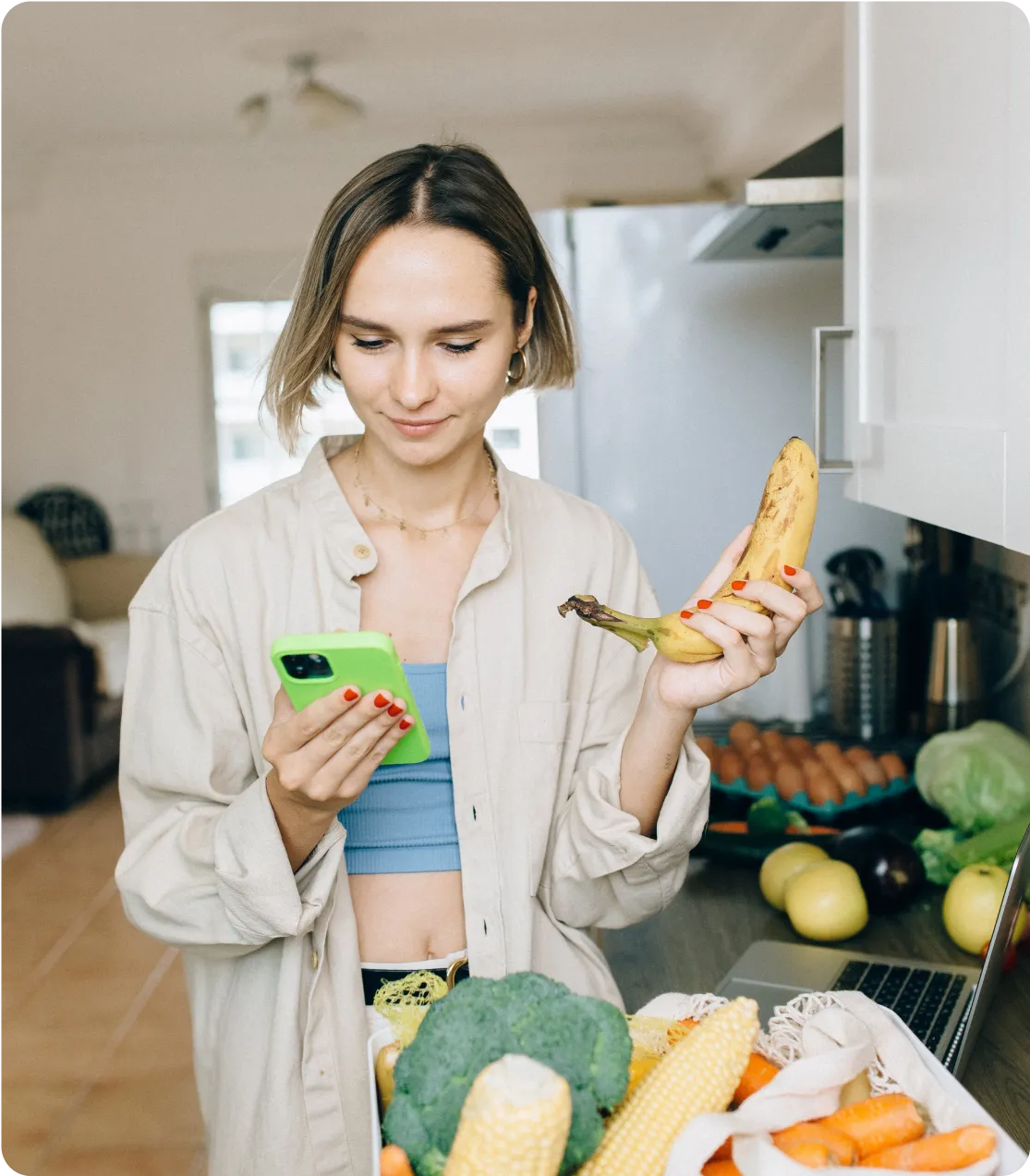 A woman is holding a phone in one hand and a vegetable in the other.