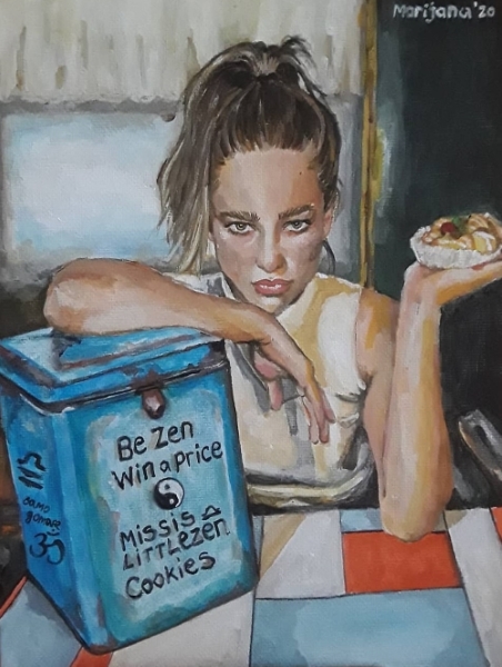 A girl is sitting at a table in a restaurant, holding a cake in one hand and resting the other on a box of biscuits