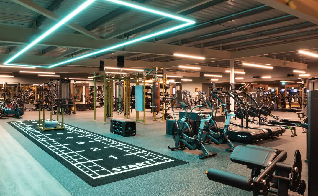 Gym floor at David Lloyd St Neots, with sprayed soffits and exposed high-level services above the cardio equipment