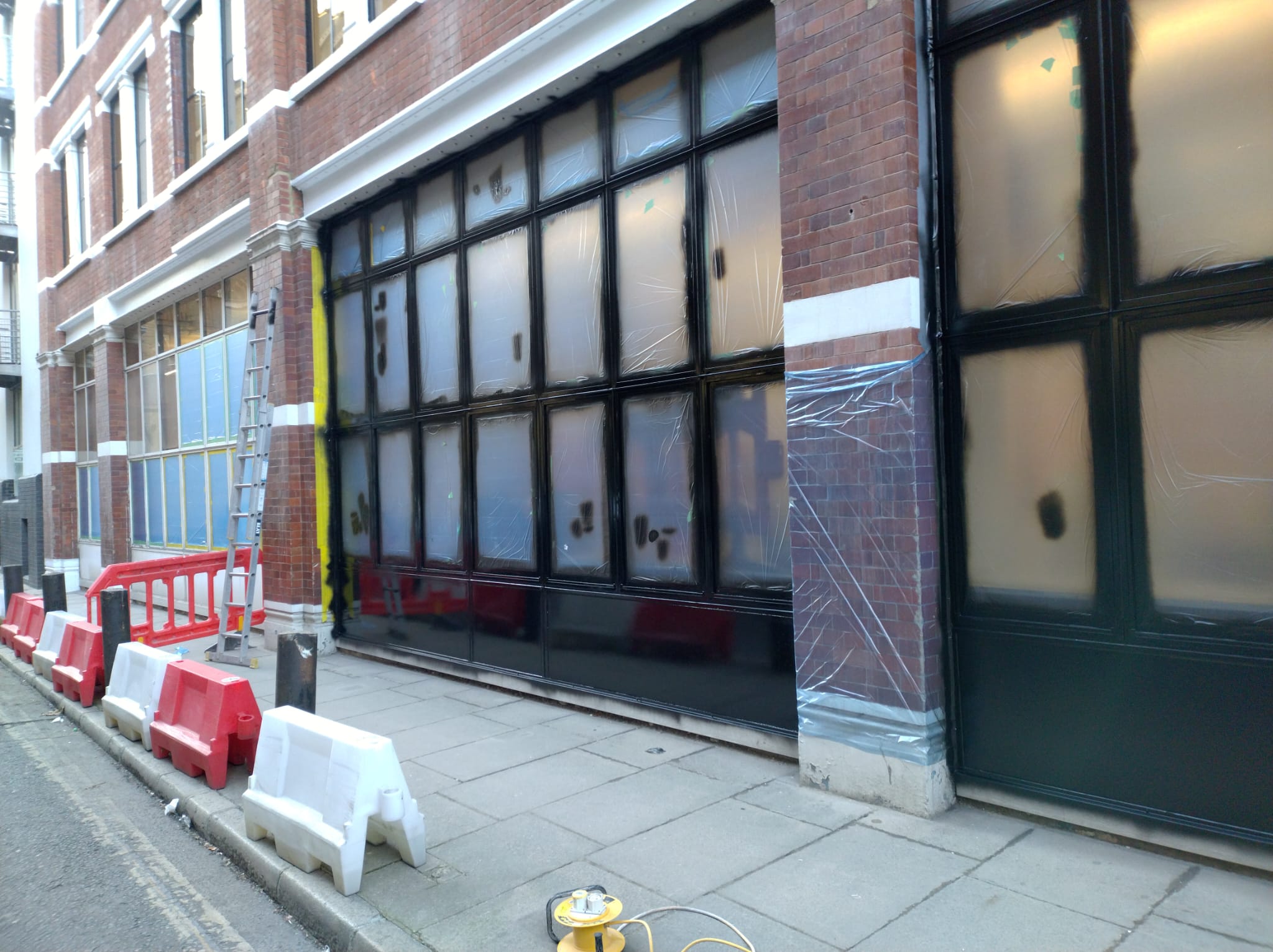 Cladding and shopfront spraying in progress on a London street