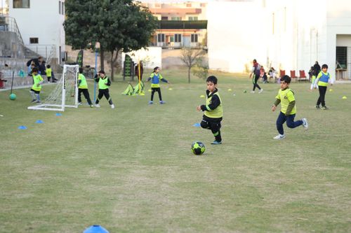 A young student prepares to kick the football while being chased down by another student