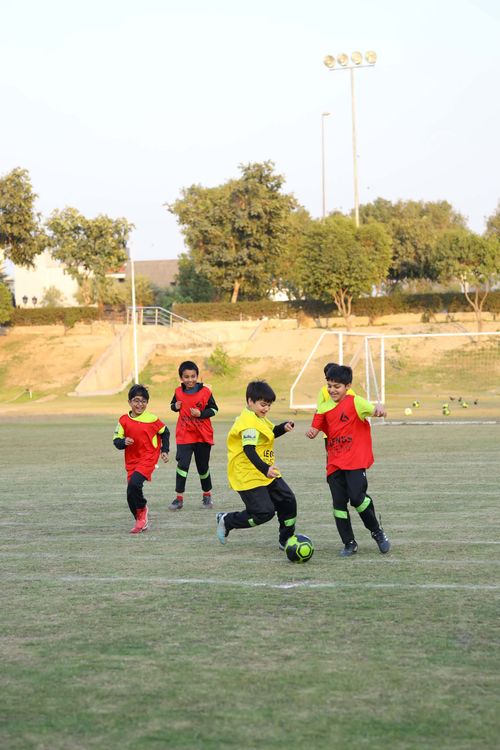 A young student prepares to change direction with the football while being closed down on by 3 students