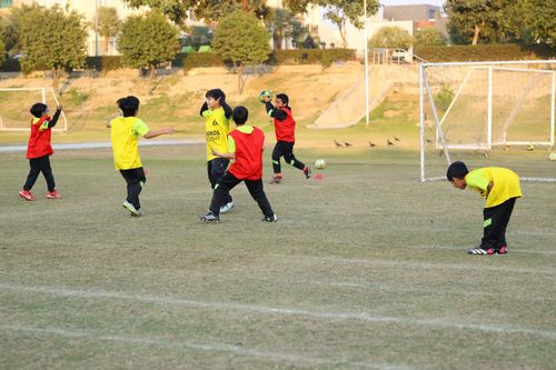 A young student celebrate by putting his hands to his ears, while being surrounded by teammates