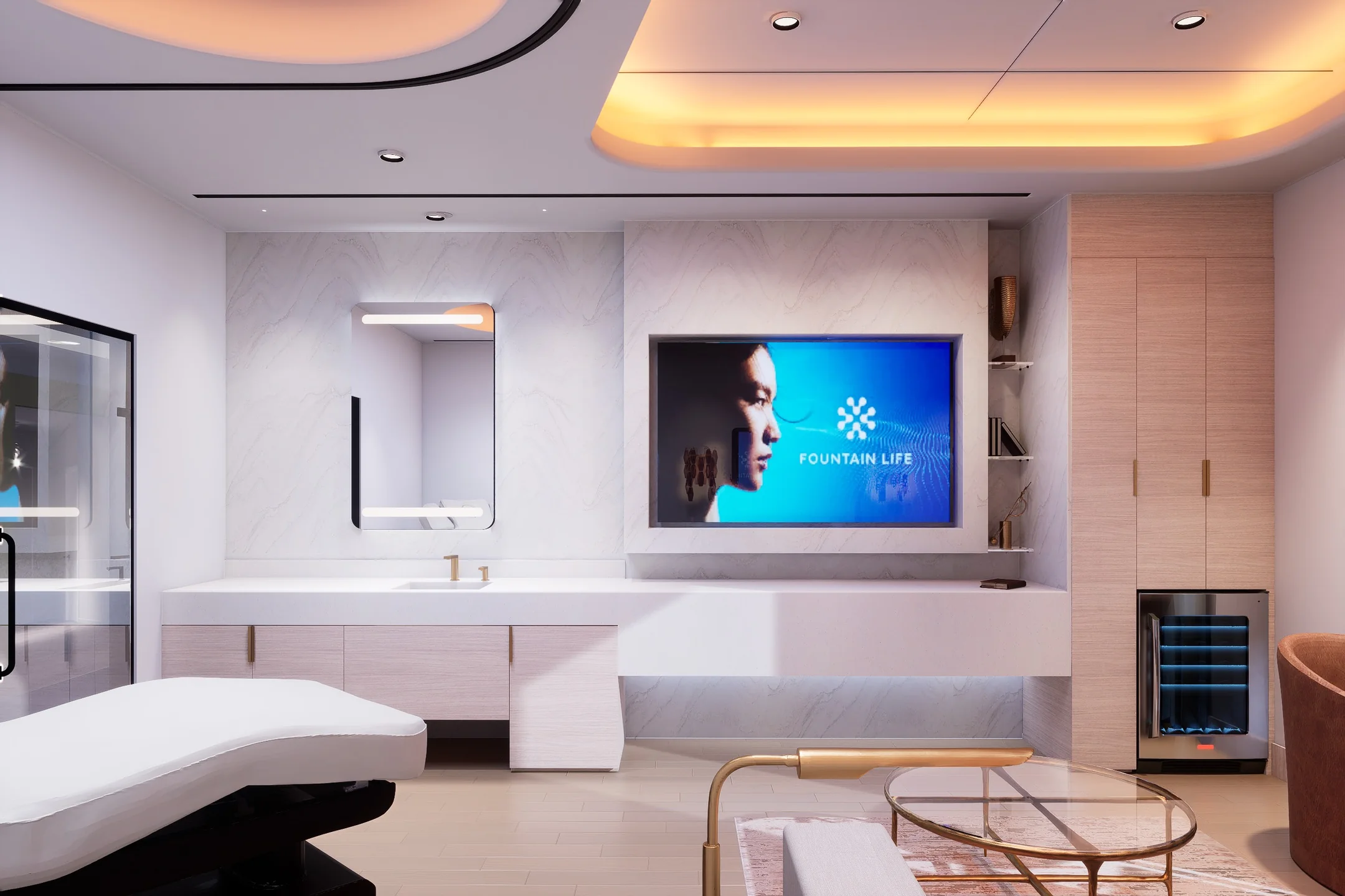 Modern clinic room with a white treatment table, large mirror above sink, built-in TV displaying "Fountain Life," and light wood cabinetry.