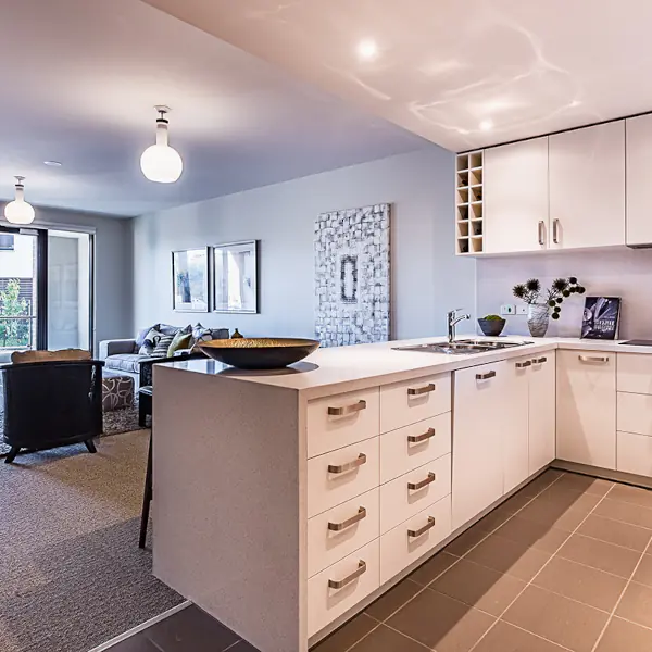 Clean white open plan kitchen in retirement unit at Mayflower Brighton.