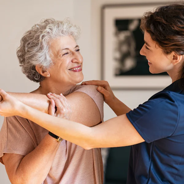 Woman in aged care stretching with care worker.