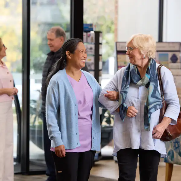 Woman and career walking and talking at the entrance of Mayflower, while another couple chat in the background.