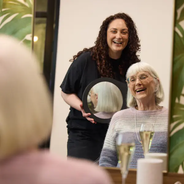An aged care resident admires her hair after getting it done at the Salon.