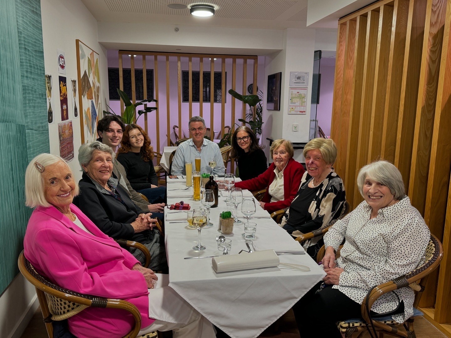 A group of smiling people sitting at a large dining table in our cafe. 
