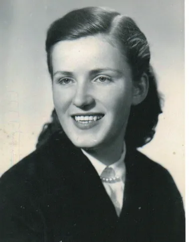 A black and white portrait of a woman smiling in the 1950s