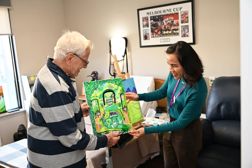 Ernie and Jancel admiring a painting of a garden by Ernie.