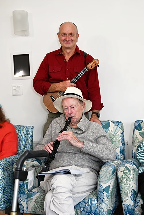Alan, stands proudly behind his dad while holding a ukelele. Peter expertly plays the clarinet.