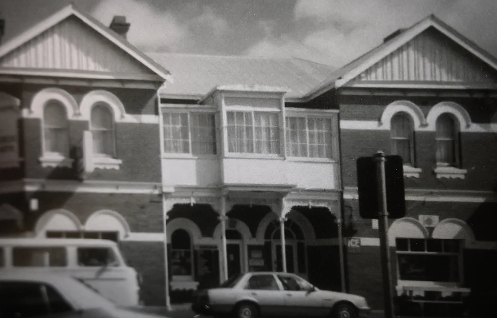 A black and white image of a big beautiful old hotel, 2 stories high