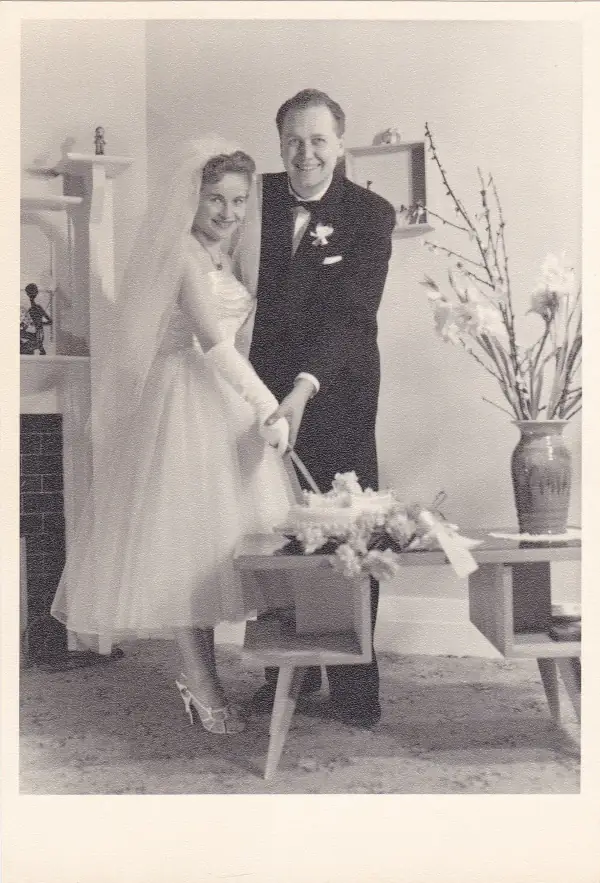 A black and white photo o Eva and Joe on their wedding day cutting the cake together.