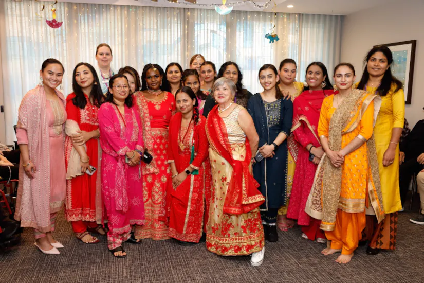 A large group of staff members smiling and wearing saris