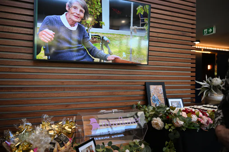 Photo of some if the dedecation decorations including Christina on a big screen, Giveaway gifts wrapped in cellophane, photos of Christina in frames, flowers, and cupcakes.