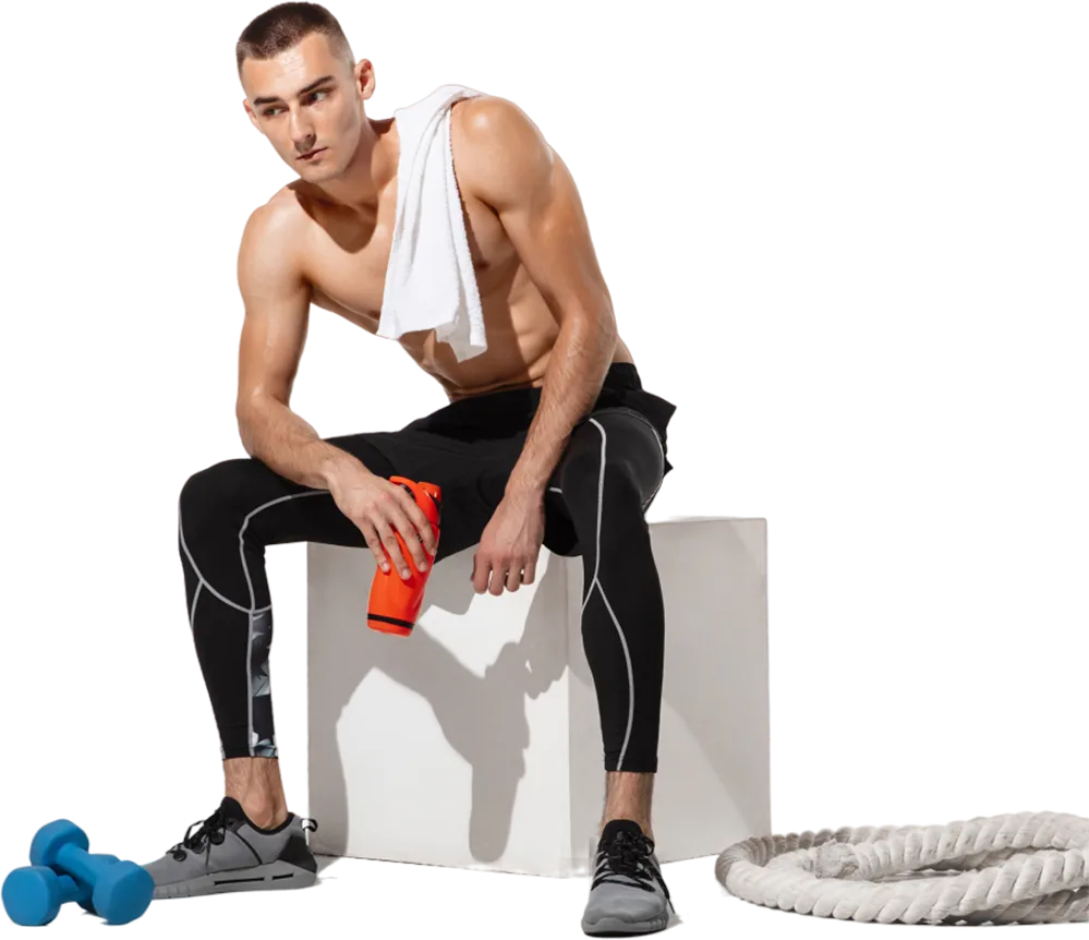 Man resting with a towel and shaker beside workout equipment