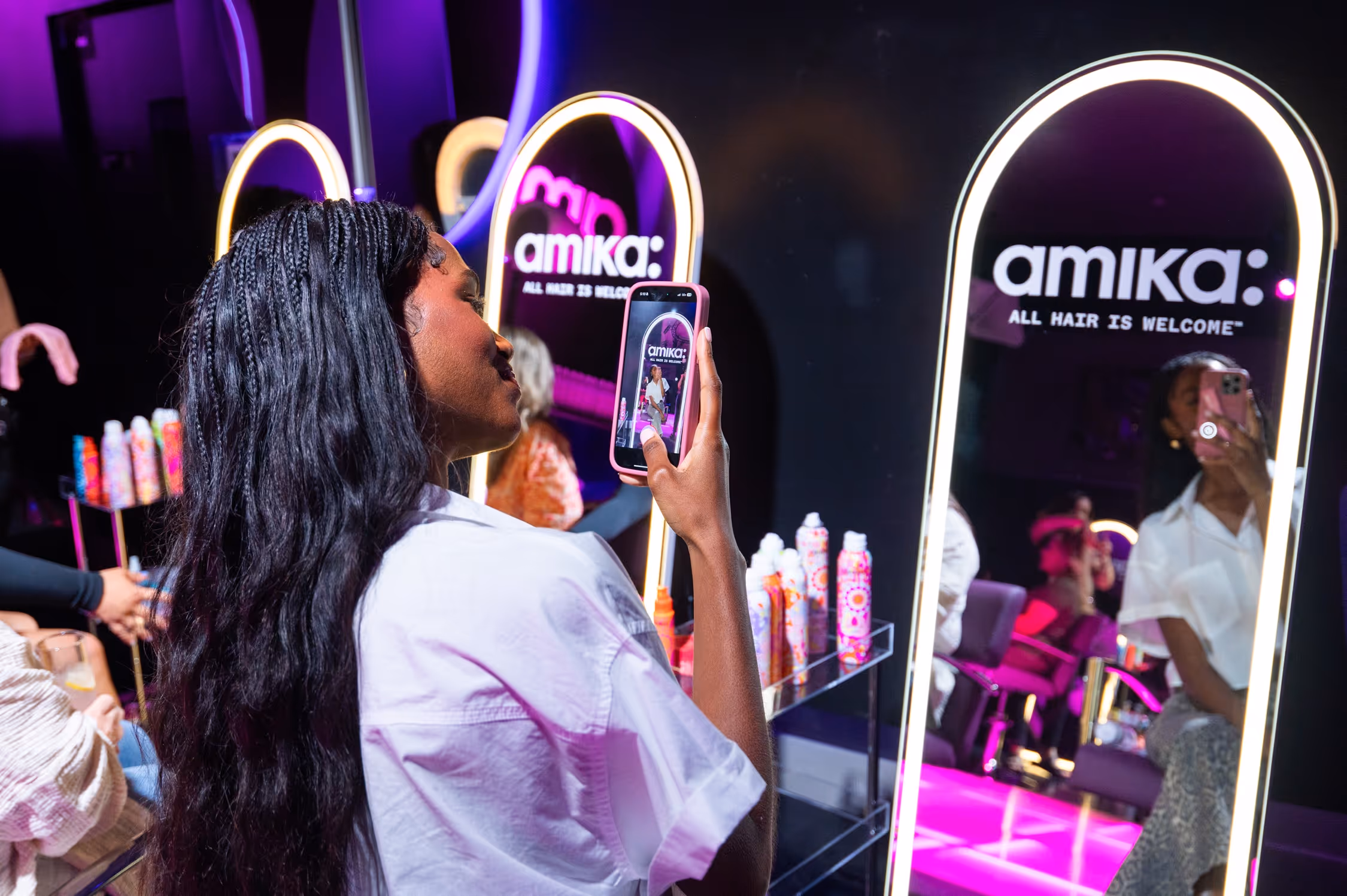 Woman taking a selfie in front of a salon-style mirror at the Amika Encore Café launch event in Nashville.