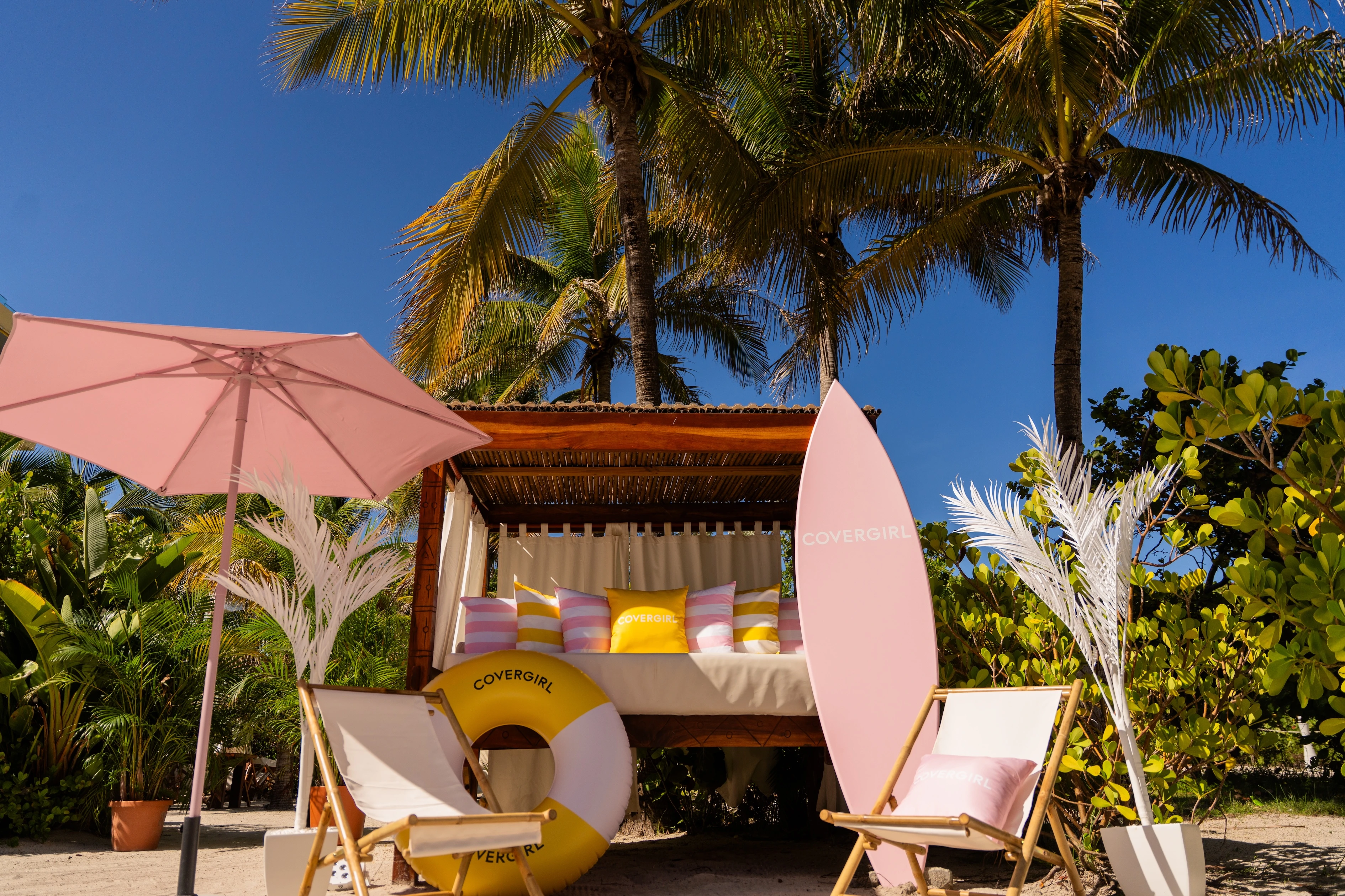 Close-up of playful, custom-built installations in bright pink and yellow tones, decorated with tropical flowers and product branding, designed to reflect the soft-focus effect of the Skin Tint.