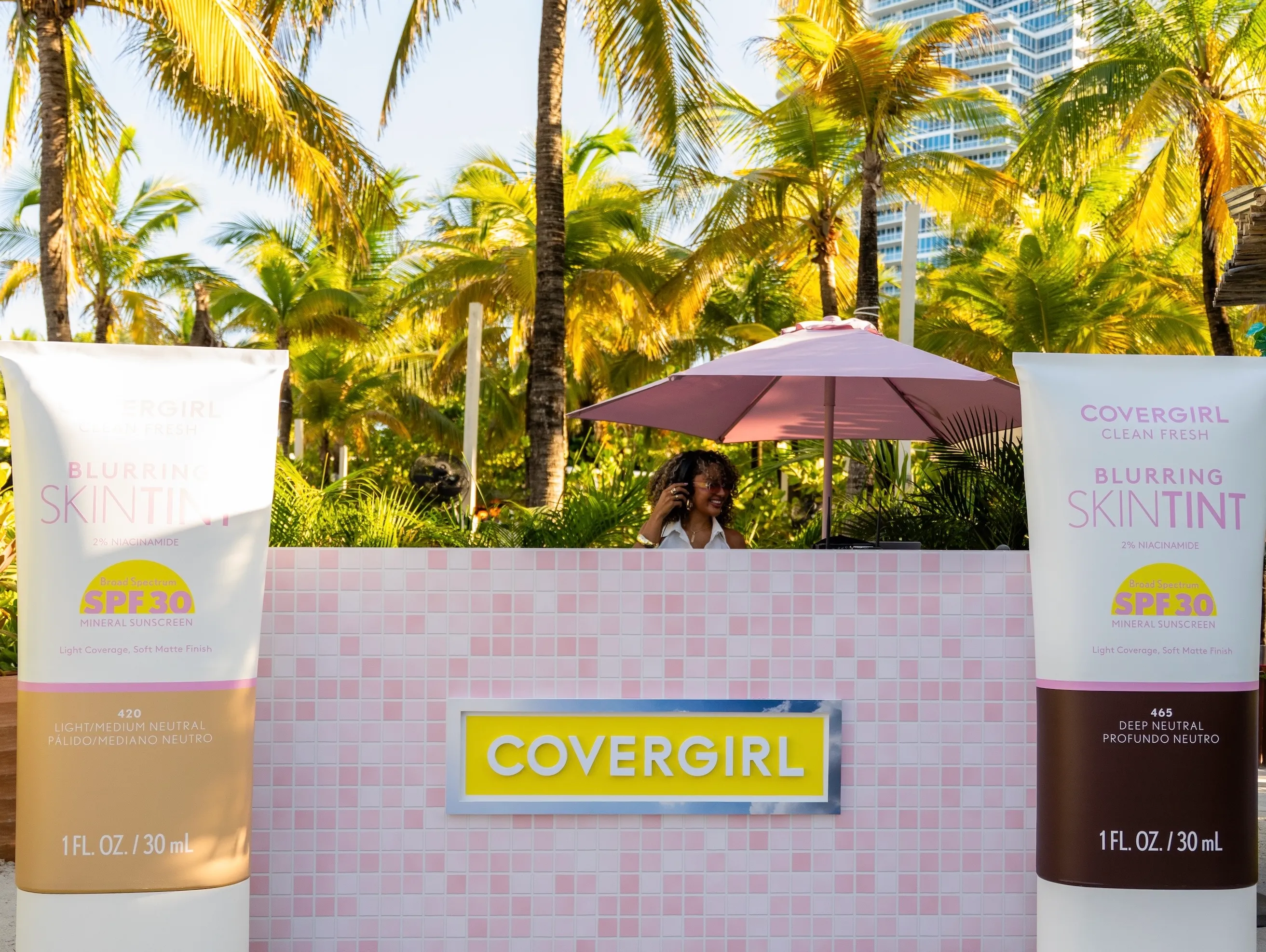 DJ performing at Blur Beach Club inside a custom pink-and-yellow booth decorated with tropical florals and COVERGIRL branding.