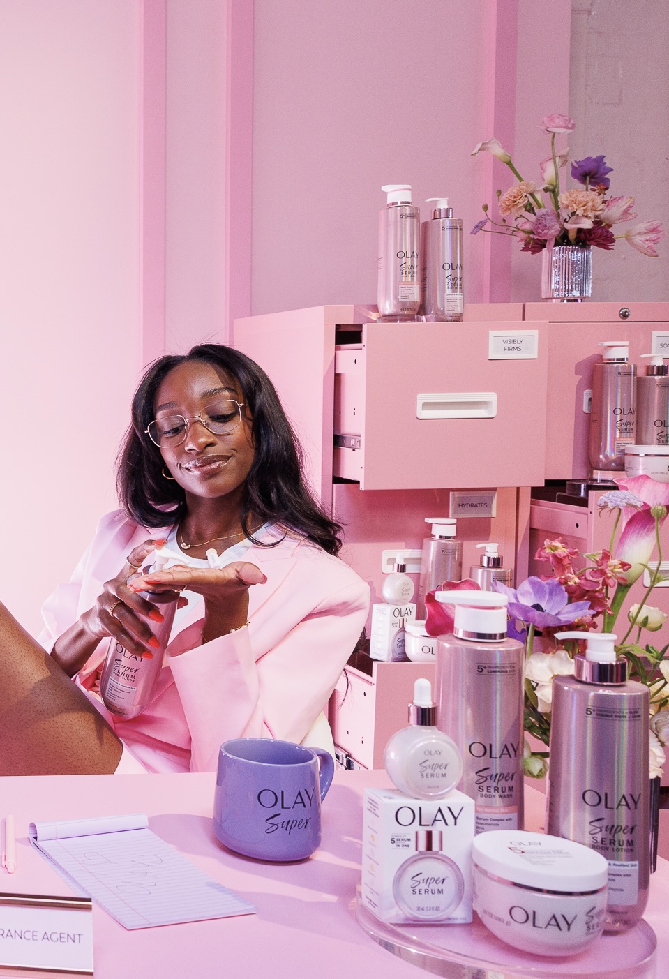Guest posing in front of a life-size COVERGIRL Clean Fresh Blurring Skin Tint installation at Blur Beach Club, surrounded by bright pink-and-yellow decor.