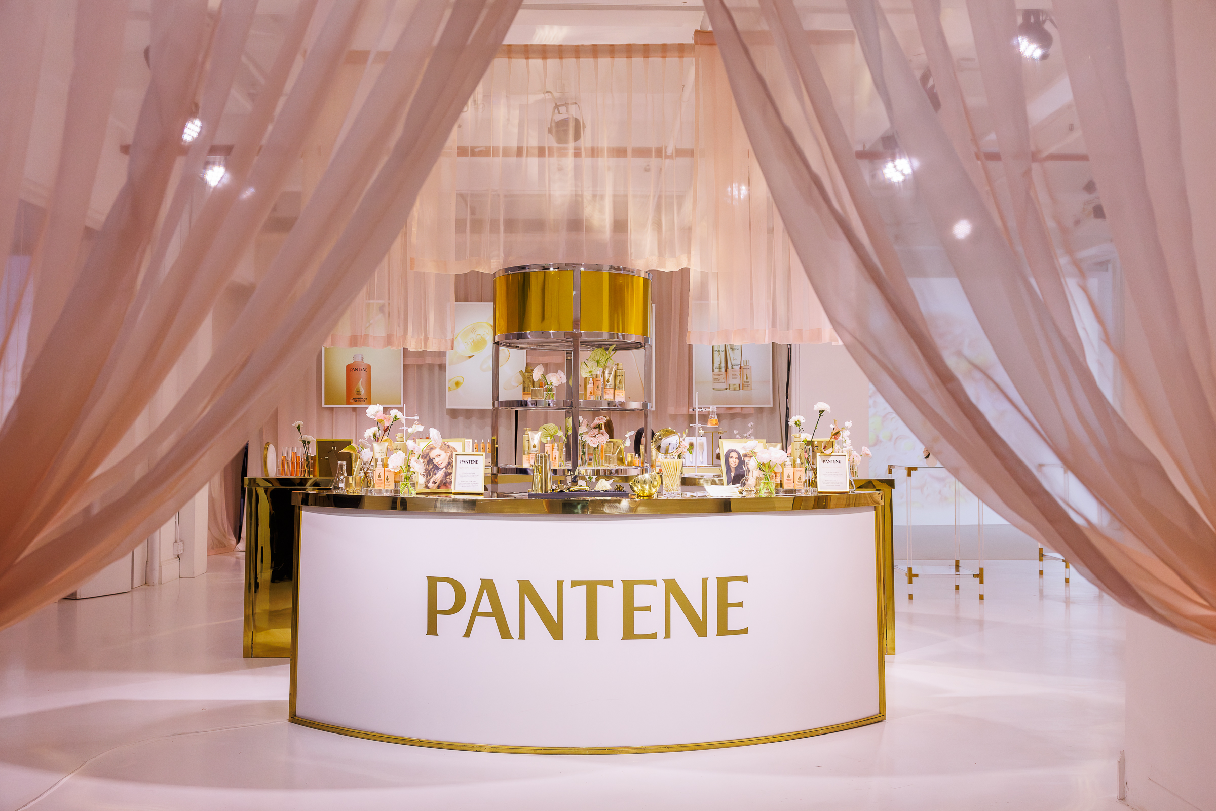Close-up of playful, custom-built installations in bright pink and yellow tones, decorated with tropical flowers and product branding, designed to reflect the soft-focus effect of the Skin Tint.