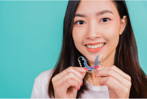 A woman holding Hawley retainers after braces treatment