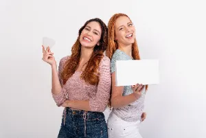 Two girls holding a Caspersmile teeth straightening kit 