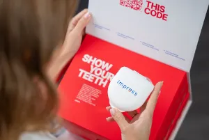 A girl holding an Impress aligner box