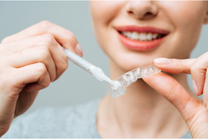 A woman applying teeth whitening gel to her tray