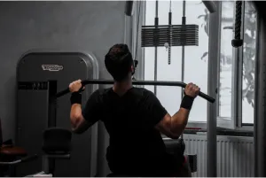 A man doing lat pull-downs in the gym