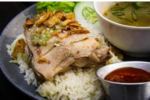 A bowl of soup with rice and grilled chicken 