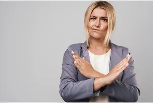 A woman making a cross sign with her hands, depicting “No”