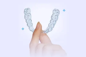 An image shows a hand holding an at-home aligner 