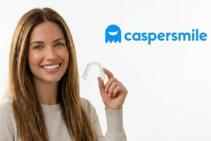 A smiling woman holding up a clear teeth aligner next to the Caspersmile logo.