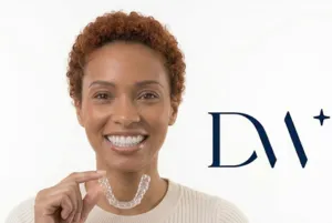 A smiling Black woman with curly auburn hair holding a clear aligner next to the
        Diamond Whites.
