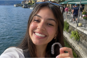 An image shows a girl holding clear aligners on vacations