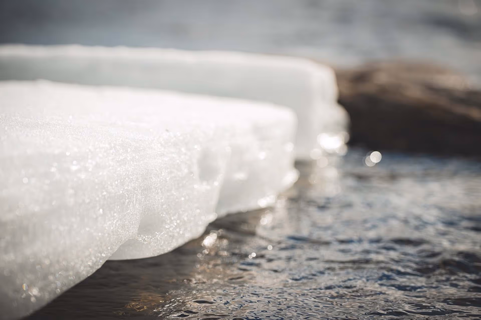 Close-up of melting ice over flowing water with a blurred background.