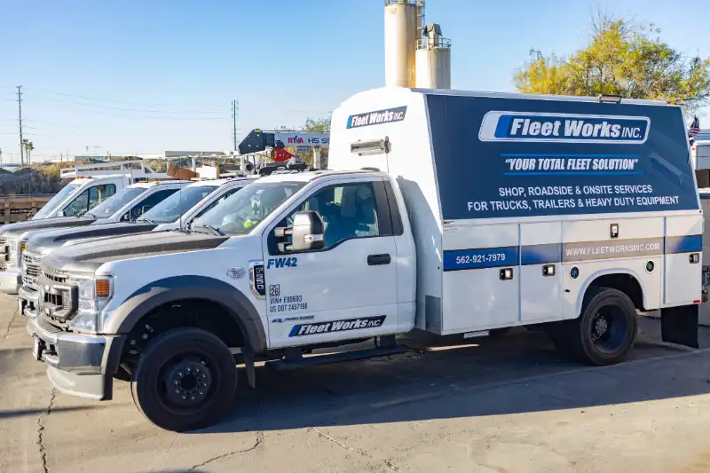 Mechanic under heavy-duty truck performing suspension repair; impact wrench, socket and ONX parts bag nearby.
