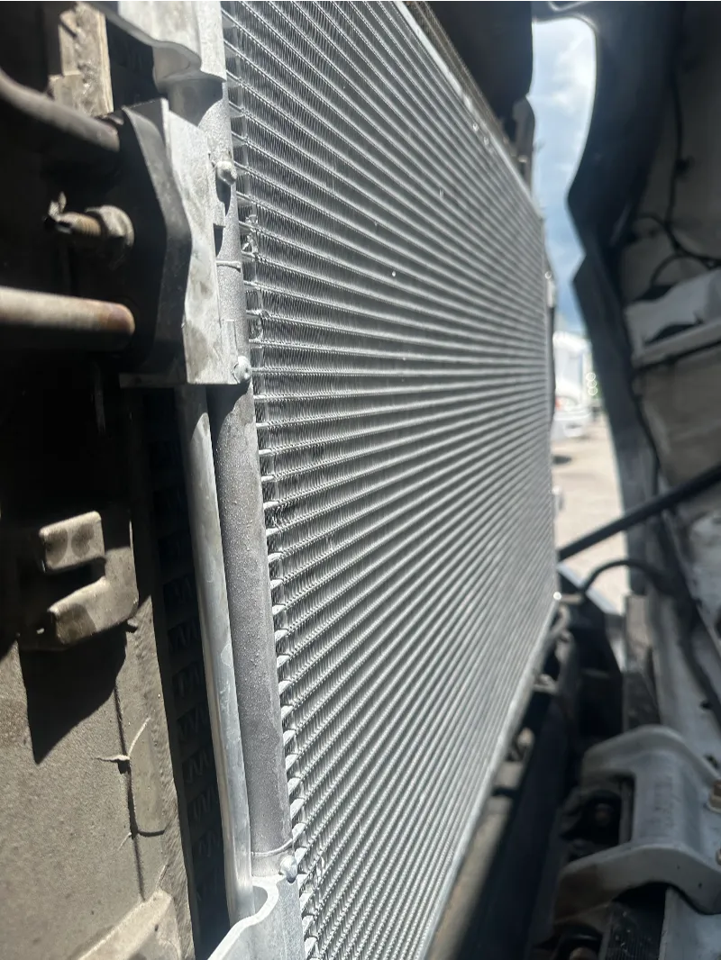 Heavy-duty radiator with clean cooling fins exposed inside a truck engine compartment.