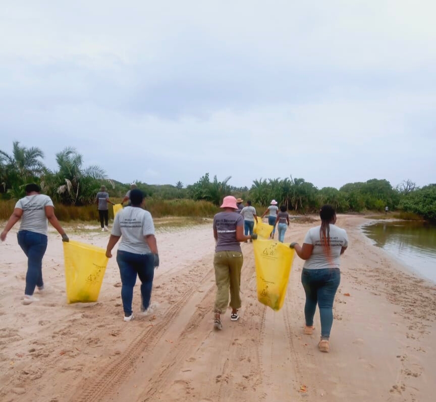 Young people carry rubbish bags across a stretch of coastline for a beach clean-up
