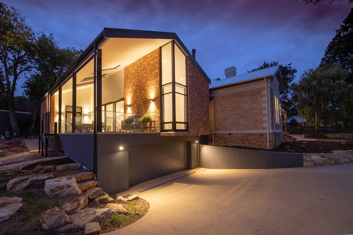 Maison moderne avec grandes fenêtres performantes éclairées au crépuscule