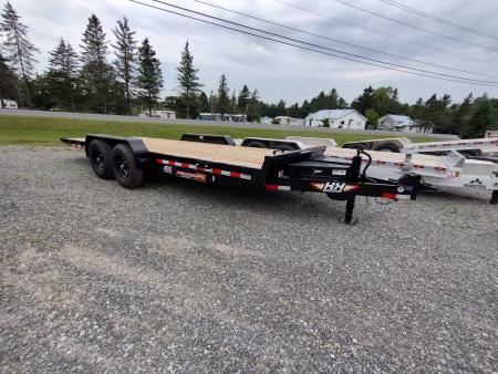 Truck towing a flatbed trailer at sunset