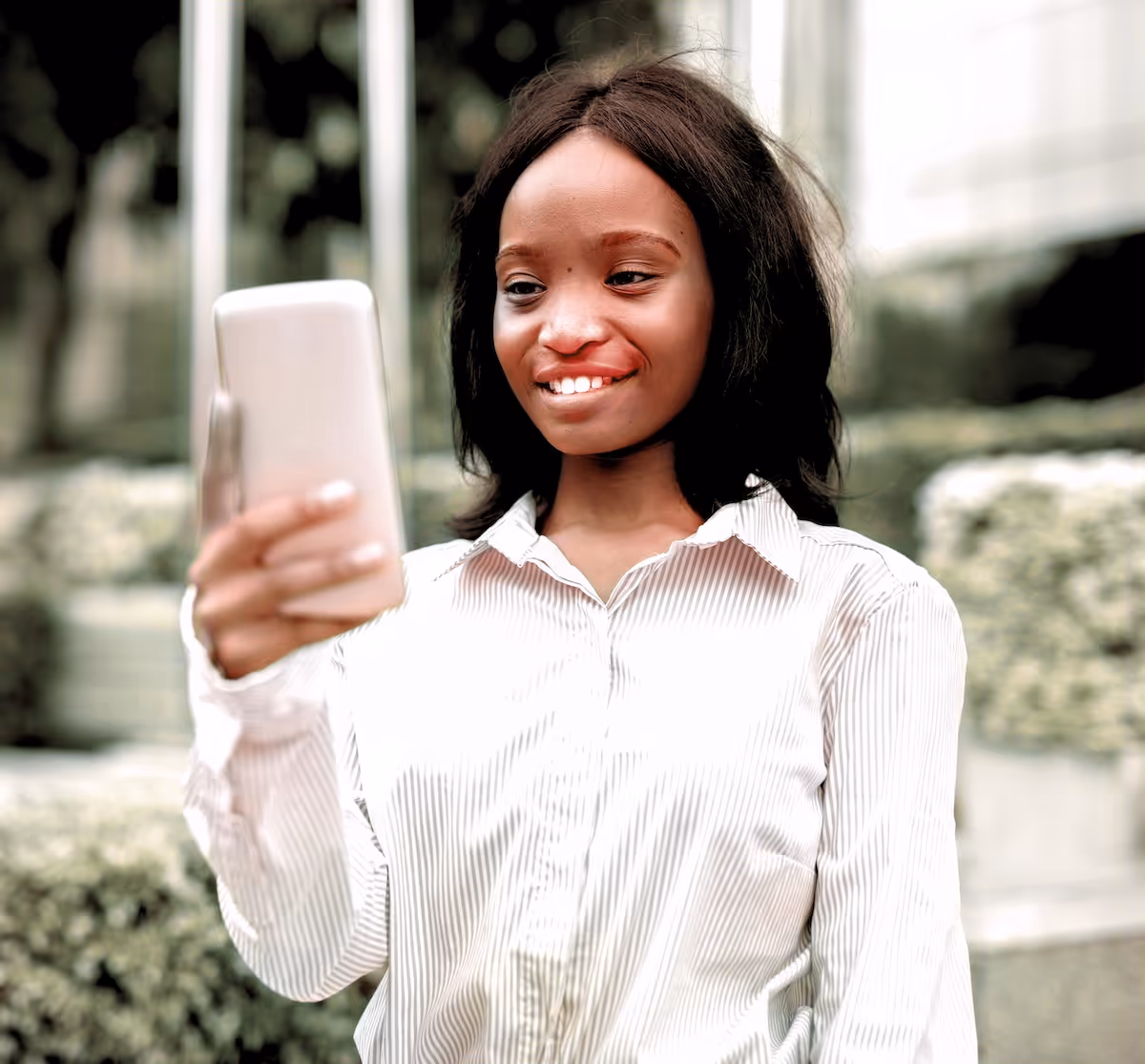 Sarah in a white shirt looking at her phone smiling
