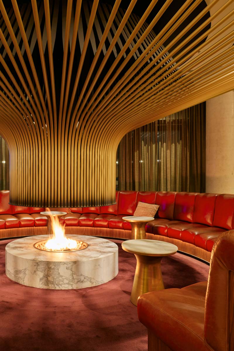 Warm luxury lounge with large circular red couch and fire pit